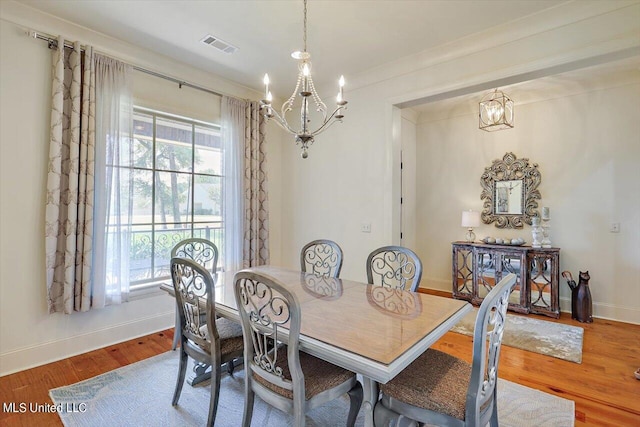 dining space with wood-type flooring and an inviting chandelier