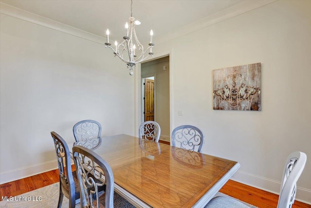 dining room featuring hardwood / wood-style flooring, ornamental molding, and an inviting chandelier