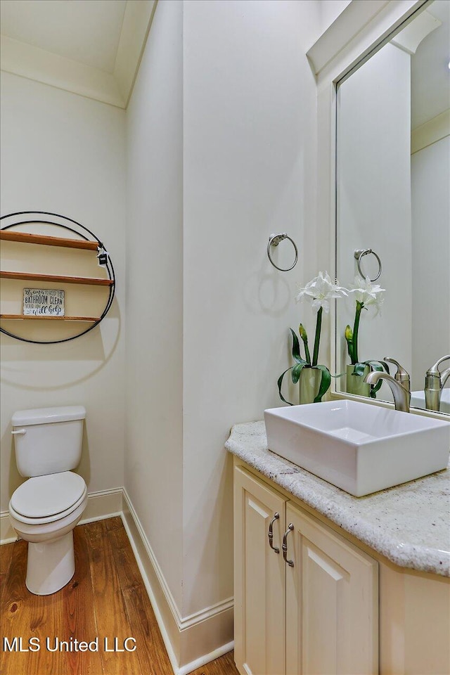 bathroom with vanity, ornamental molding, hardwood / wood-style flooring, and toilet