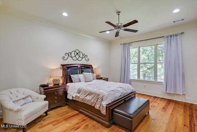 bedroom with light hardwood / wood-style flooring, crown molding, and ceiling fan