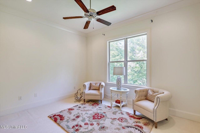 sitting room featuring light carpet, ornamental molding, and ceiling fan