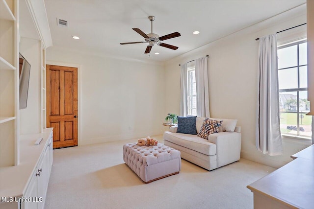 carpeted living room with crown molding and ceiling fan