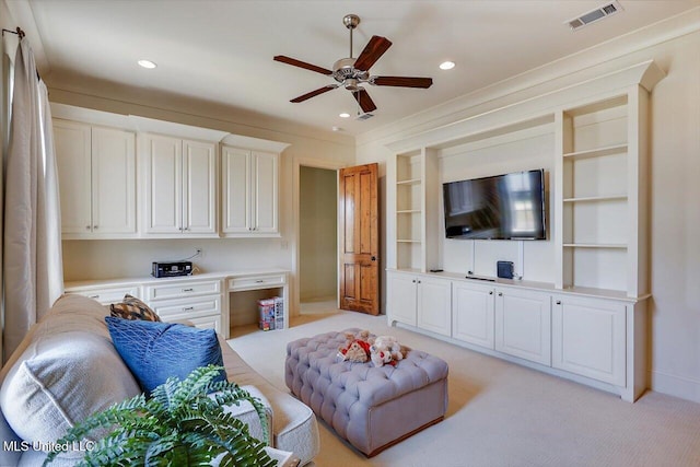 carpeted living room featuring built in desk and ceiling fan