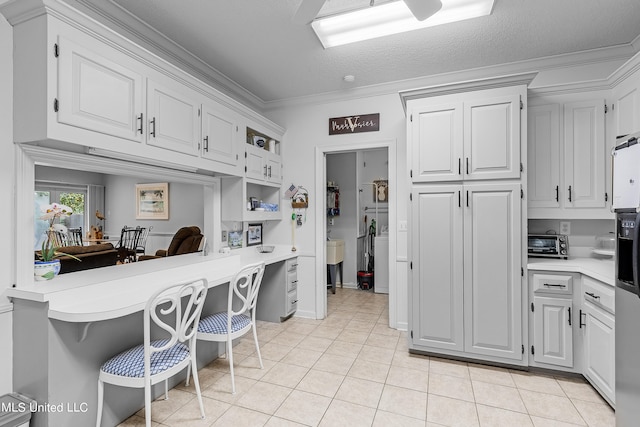 kitchen featuring ornamental molding, a breakfast bar, white cabinets, and a textured ceiling