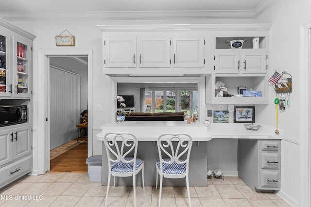 kitchen with ornamental molding, light tile patterned flooring, a kitchen bar, and white cabinets