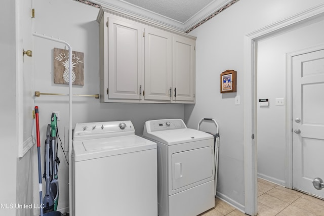 laundry room with ornamental molding, separate washer and dryer, light tile patterned floors, a textured ceiling, and cabinets