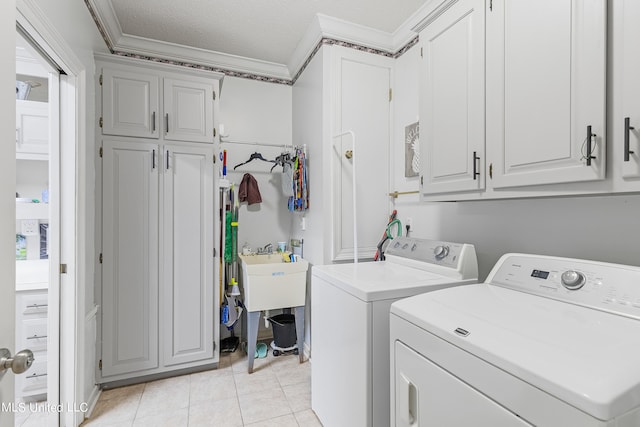 clothes washing area with crown molding, light tile patterned flooring, cabinets, a textured ceiling, and washing machine and dryer