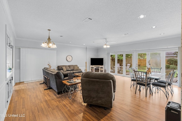 living room featuring light wood-type flooring, ceiling fan with notable chandelier, french doors, a textured ceiling, and ornamental molding