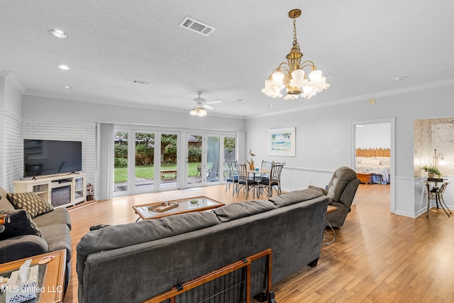 living room featuring ornamental molding, light hardwood / wood-style flooring, a textured ceiling, and ceiling fan with notable chandelier