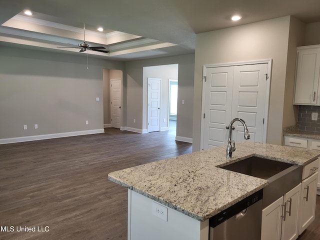 kitchen with a center island with sink, a raised ceiling, sink, ornamental molding, and white cabinetry