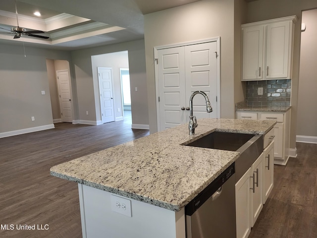 kitchen featuring white cabinets, dishwasher, an island with sink, and a tray ceiling