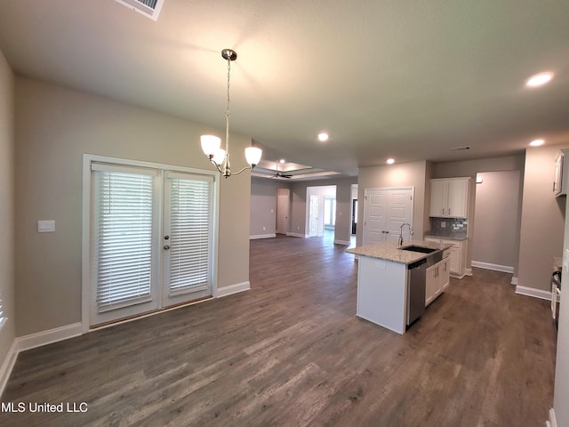 kitchen featuring pendant lighting, a center island with sink, sink, stainless steel dishwasher, and white cabinetry