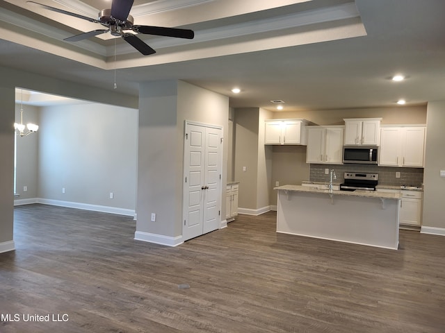 kitchen featuring white cabinets, appliances with stainless steel finishes, a tray ceiling, and light stone countertops