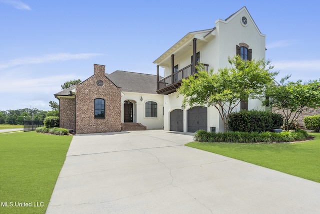 view of front facade featuring a balcony, driveway, a front yard, a garage, and a chimney