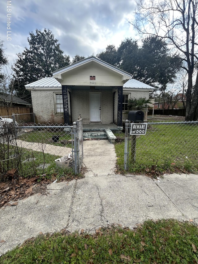 bungalow with a gate, a porch, a fenced front yard, brick siding, and metal roof