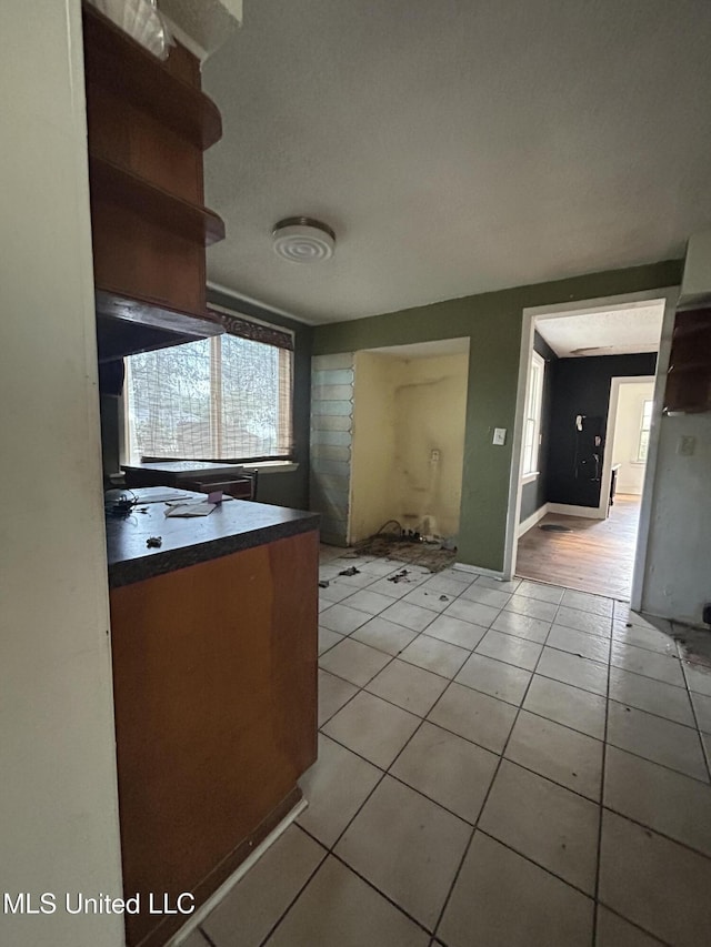 kitchen with dark countertops, light tile patterned flooring, and baseboards