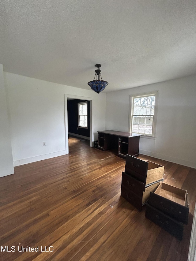 living area featuring baseboards, dark wood-style flooring, a wealth of natural light, and a textured ceiling