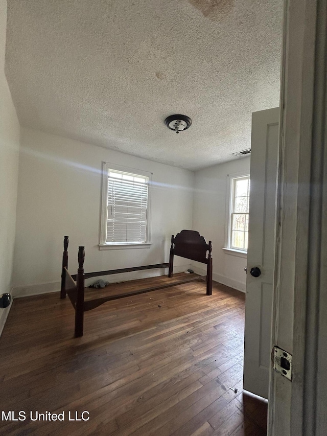 unfurnished bedroom featuring dark wood-style floors, a textured ceiling, and baseboards