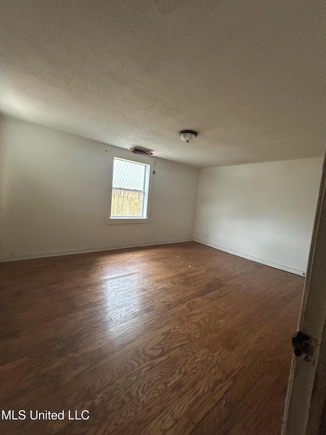 empty room with wood finished floors and a textured ceiling