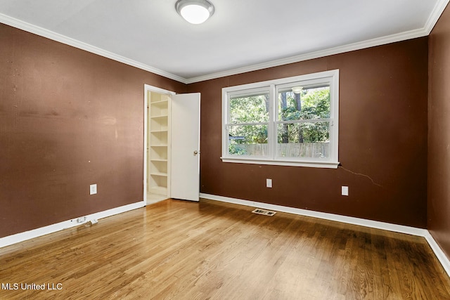 spare room with ornamental molding and hardwood / wood-style floors