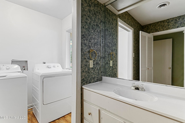 bathroom with vanity, separate washer and dryer, and hardwood / wood-style floors