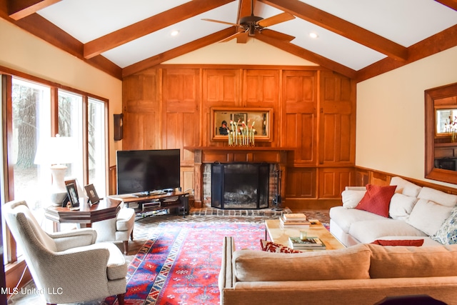 living room featuring vaulted ceiling with beams, ceiling fan, and a brick fireplace