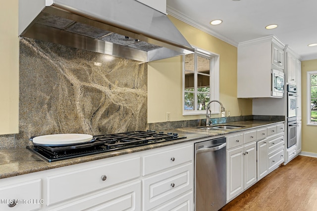 kitchen with stainless steel appliances, wall chimney exhaust hood, sink, and plenty of natural light