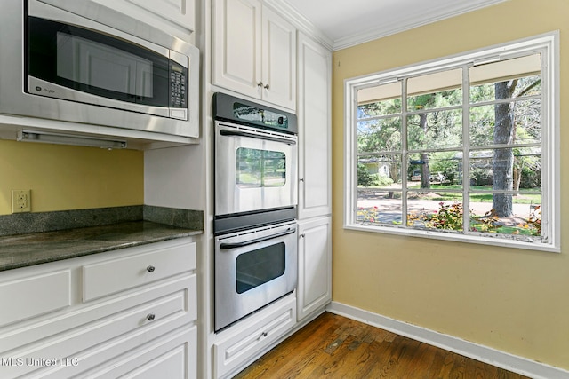 kitchen featuring dark wood-type flooring, appliances with stainless steel finishes, crown molding, and white cabinets