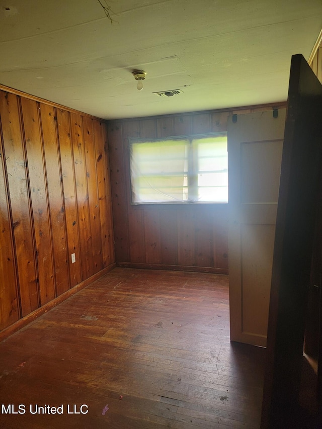 spare room with wood walls and dark hardwood / wood-style flooring