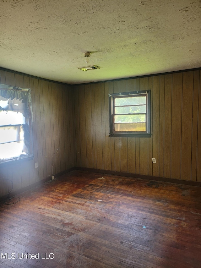 unfurnished room with wood walls and dark hardwood / wood-style floors