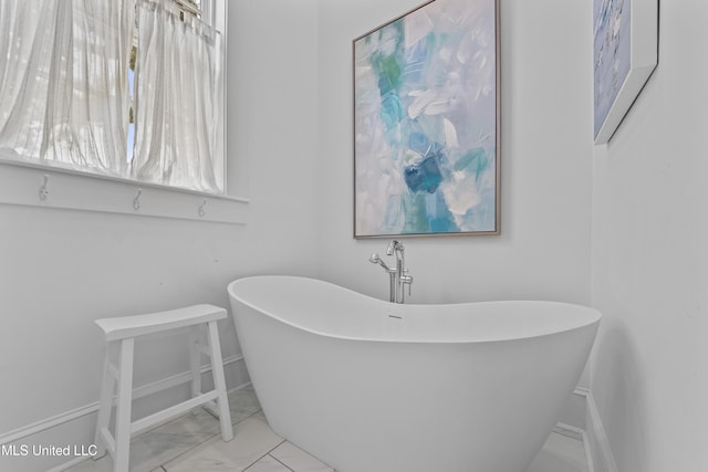 1221 E Beach Blvd, Pass Christian, MS 39571 - bathroom with marble finish flooring, a freestanding bath, and baseboards