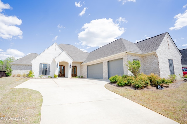 french provincial home with a front yard and a garage