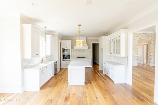 kitchen featuring white cabinetry, decorative light fixtures, and stainless steel appliances