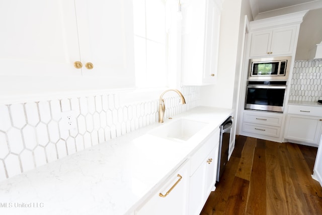 kitchen featuring sink, white cabinets, dark hardwood / wood-style flooring, appliances with stainless steel finishes, and tasteful backsplash