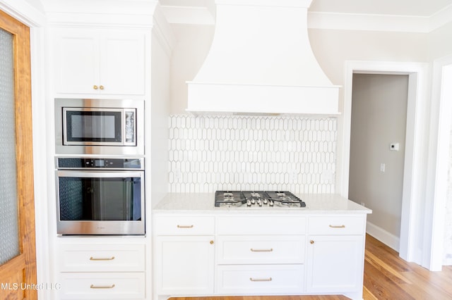 kitchen featuring appliances with stainless steel finishes, custom exhaust hood, and white cabinetry