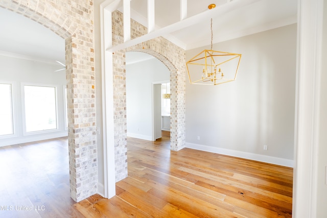 empty room featuring ornamental molding, an inviting chandelier, and hardwood / wood-style floors