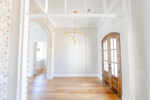 foyer featuring an inviting chandelier, hardwood / wood-style floors, and french doors