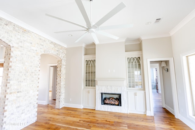 unfurnished living room with light hardwood / wood-style floors, ornamental molding, and ceiling fan