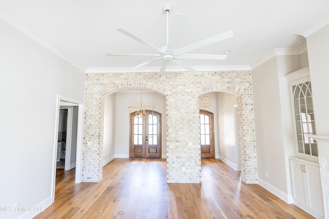 interior space featuring light hardwood / wood-style floors, french doors, ornamental molding, and ceiling fan with notable chandelier