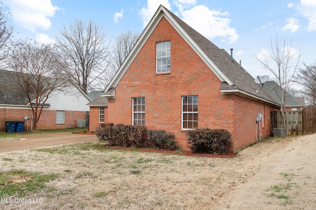 view of side of property featuring central air condition unit, fence, and brick siding