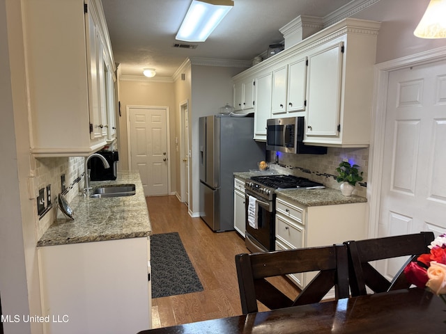 2043 Branch Creek Dr, Byram, MS 39272 - kitchen with stainless steel appliances, white cabinetry, backsplash, light wood-style flooring, and ornamental molding