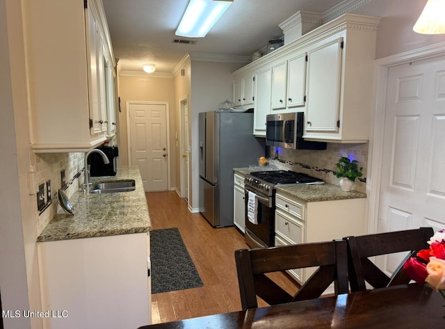 2043 Branch Creek Dr, Byram, MS 39272 - kitchen featuring stainless steel appliances, backsplash, white cabinets, light wood-style floors, and crown molding
