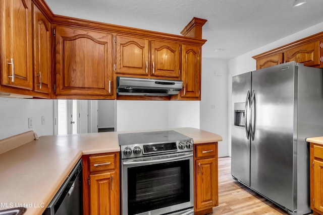 16609 Old River Rd, Vancleave, MS 39565 - kitchen featuring stainless steel appliances, under cabinet range hood, light wood finished floors, and brown cabinetry