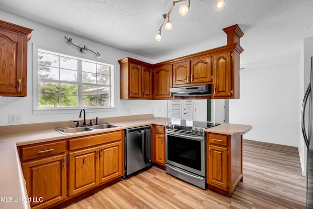 16609 Old River Rd, Vancleave, MS 39565 - kitchen featuring stainless steel appliances, under cabinet range hood, a sink, light wood-style floors, and brown cabinetry
