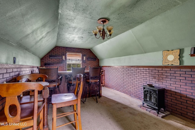 16609 Old River Rd, Vancleave, MS 39565 - sitting room featuring brick wall, vaulted ceiling, a wood stove, carpet floors, and a bar