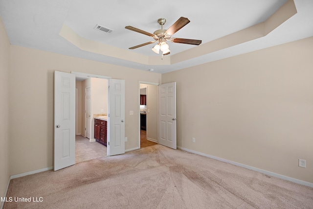 217 Belle Chasse Cir, Jackson, MS 39272 - unfurnished bedroom featuring light colored carpet, a tray ceiling, baseboards, connected bathroom, and a ceiling fan