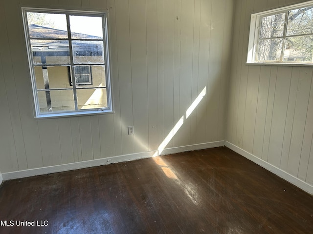 spare room featuring dark wood-style floors, baseboards, and a wealth of natural light