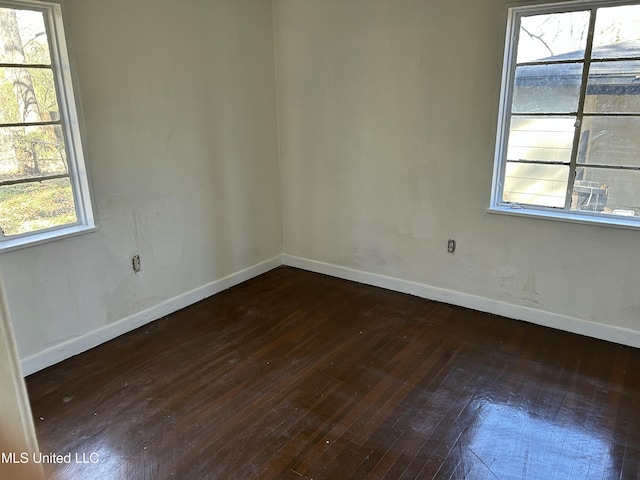 empty room with baseboards and wood-type flooring