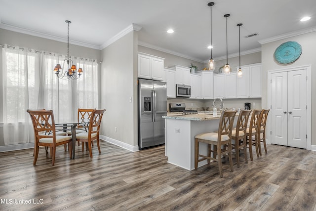 kitchen featuring light stone countertops, a center island with sink, white cabinets, and stainless steel appliances