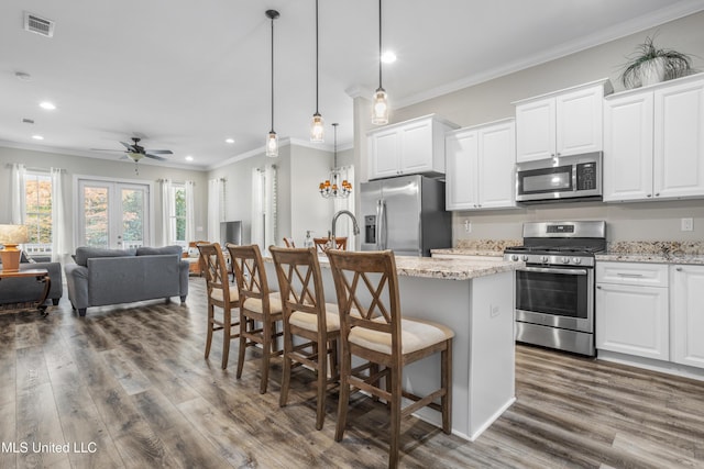 kitchen featuring a breakfast bar, appliances with stainless steel finishes, white cabinetry, and light stone counters